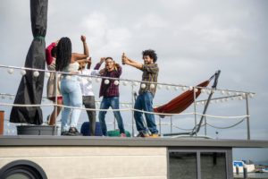 A cheerful group of friends celebrating on a yacht, capturing memories with their smartphones.