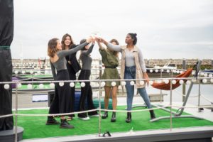 A joyful group of women raising glasses to celebrate on a yacht deck in Portugal.